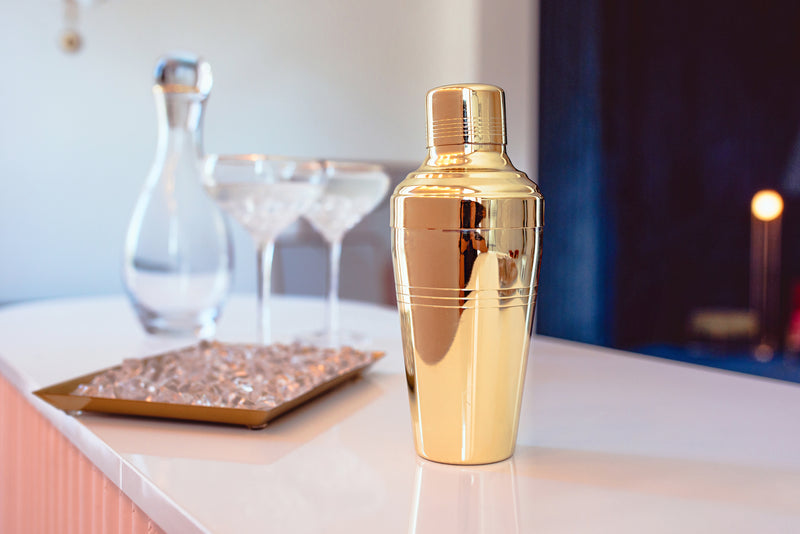 Gold cocktail shaker with martini glasses and napkins